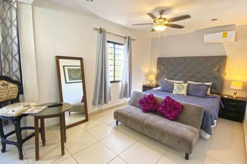 een slaapkamer met een bank en een bed met paarse kussens bij Beachside Oasis ! Spacious ½ block from the Beach in Puerto Morelos