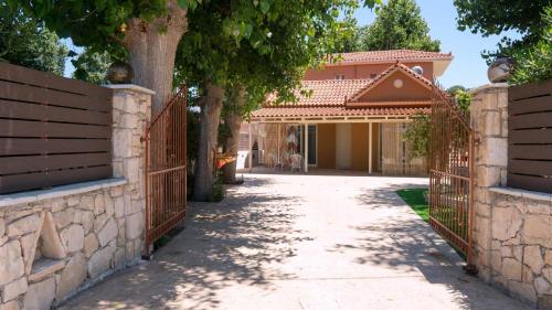 a driveway leading to a house with a gate and trees at Beach House Lefkes in Plános