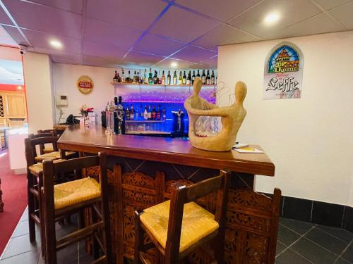 a bar with a statue of two people sitting at it at Hotel Le Saint Aubin in Gournay-en-Bray