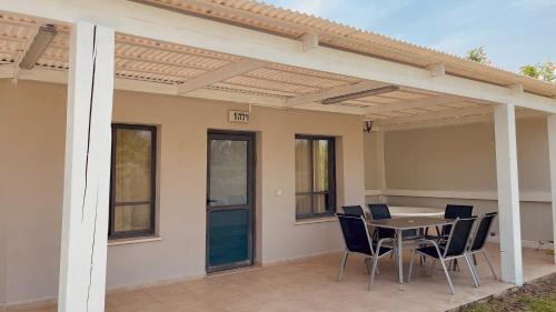 um pátio com uma pérgola, uma mesa e cadeiras em Nofey Habashan em Lahavot HaBashan