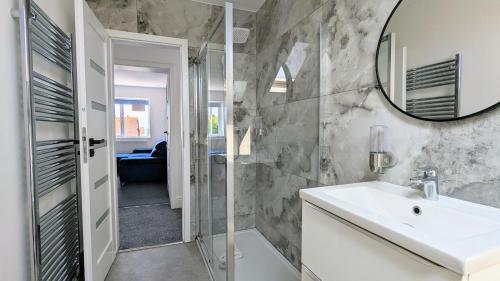 a bathroom with a sink and a mirror at Sandy Beach Apartment by Seaside Llandudno in Llandudno