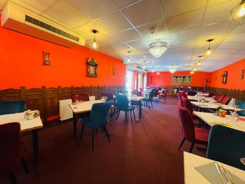 a dining room with tables and chairs and red walls at Hotel Le Saint Aubin in Gournay-en-Bray