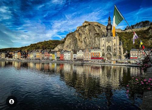 a town next to a body of water with a church at Maison Nasko in Dinant