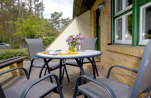 a patio table with chairs and a vase of purple flowers at Ferienhaus Wolters in Ostseebad Karlshagen