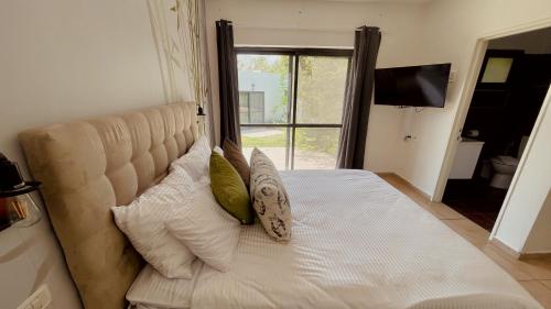 a bedroom with a bed with pillows and a window at נופי הבשן - חדרי אירוח מושלמים לזוגות ומשפחות בלהבות הבשן in Lahavot HaBashan