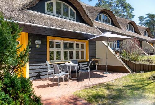 a patio with a table and chairs and an umbrella at Ferienhaus Wolters in Ostseebad Karlshagen