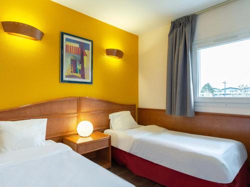 een hotelkamer met 2 bedden en een raam bij B&B HOTEL Strasbourg Nord Mundolsheim in Mundolsheim