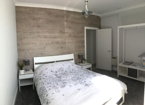 a bedroom with a white bed and a wooden wall at The Bolthole in Limekilns