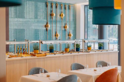 a dining room with tables and chairs and windows at Hotel Linea Mare in Pobierowo