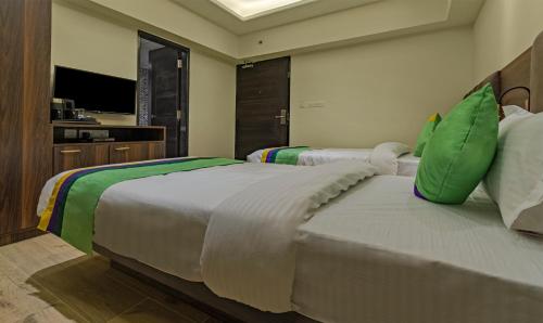two beds with green pillows in a hotel room at Treebo Pink City Grand in Jaipur