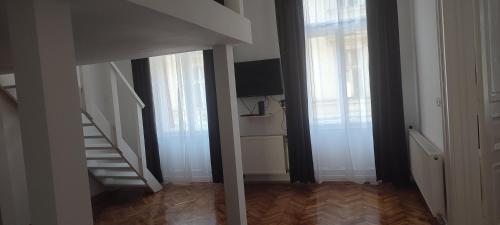 a hallway with white walls and stairs and windows at Kriston Apartman 2 in Miskolc