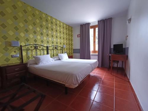 a bedroom with a bed and a yellow wall at Hotel Rural Cuartamenteru in Llanes