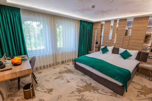 Un dormitorio con una cama con sábanas verdes y una mesa. en Hotel Codrişor, en Bistriţa