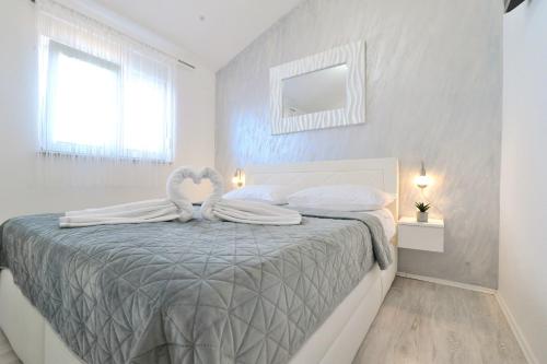 1 dormitorio blanco con 1 cama con toalla de cisne en Shine Luxury, en Maslenica