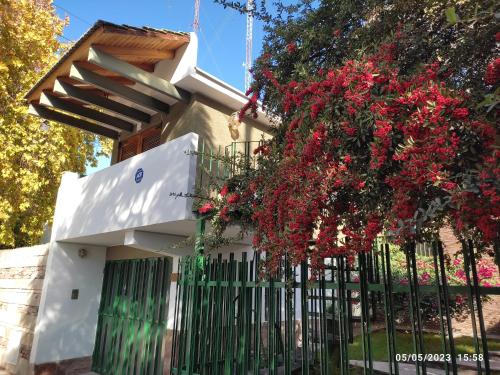 una casa blanca con una valla y flores rojas en DEPARTAMENTO San Jorge en Mendoza