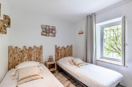 two beds in a room with a window at Chambres d'Hôtes Château Pierre de Montignac in Civrac-en-Médoc