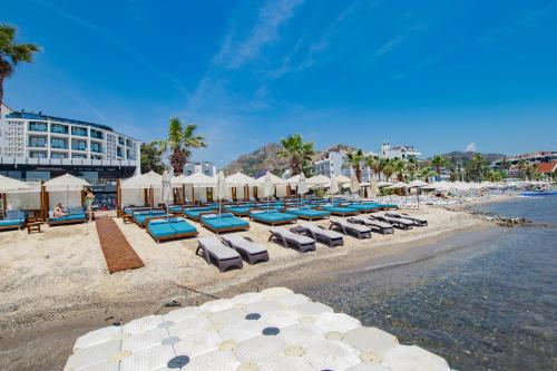 a beach with lounge chairs and umbrellas and the ocean at Class Unique Beach in Marmaris