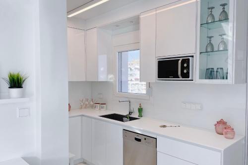 a white kitchen with a sink and a microwave at Euphoria luxury penthouse in Kavala
