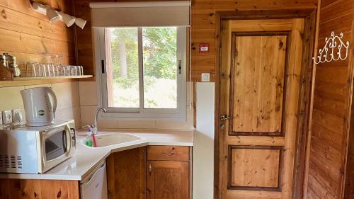 a kitchen with a microwave and a sink and a window at נופי הבשן - חדרי אירוח מושלמים לזוגות ומשפחות בלהבות הבשן in Lahavot HaBashan