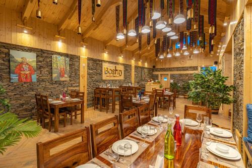 um restaurante com mesas e cadeiras de madeira e uma parede de tijolos em StayVista at DAAFI House with Comp Breakfast em Theog