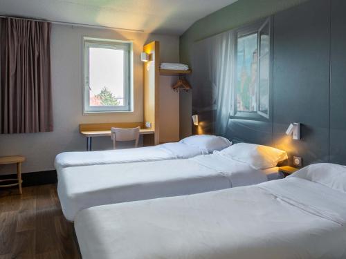 フェンデンハイムにあるB&B HOTEL Strasbourg Nord Artisansのベッド3台とテーブルが備わるホテルルームです。