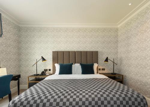 a bedroom with a large bed with blue pillows at The City of London Club in London