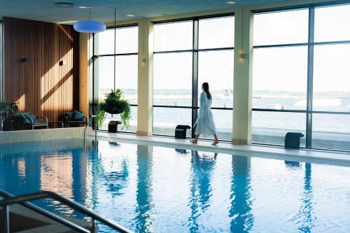 a woman in a white dress walking by a swimming pool at Struer Grand Hotel in Struer