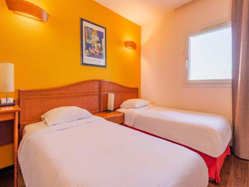 - 2 lits dans une chambre d'hôtel aux murs jaunes dans l'établissement B&B HOTEL Strasbourg Aéroport, à Holtzheim