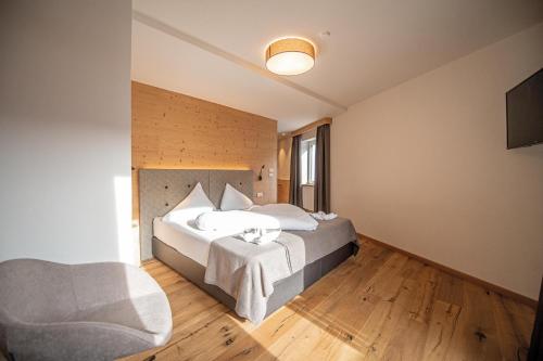 a hotel room with a bed and a chair at Gasthof Teiser Stern in Funes