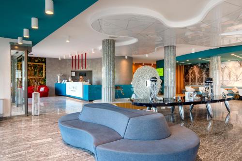 a lobby with a blue couch and a table at B&B Hotel Chioggia Airone in Sottomarina