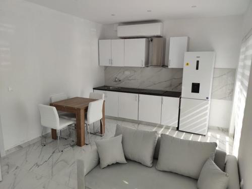 een woonkamer met een bank en een tafel en een keuken bij Alex Apartments Skiathos in Skiathos-stad