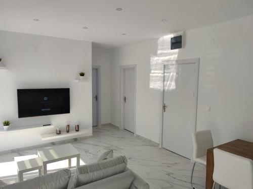 a living room with a couch and a tv on a wall at Alex Apartments Skiathos in Skiathos Town