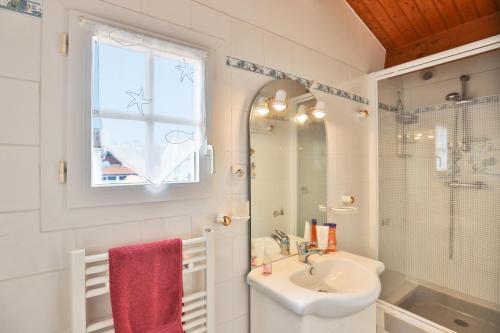 La salle de bains blanche est pourvue d'un lavabo et d'un miroir. dans l'établissement Camping Le Petit Rocher, à Longeville-sur-Mer