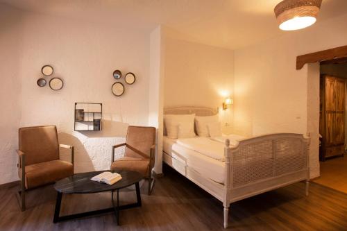 a bedroom with a bed and two chairs and a table at Hotel Hüttenmühle Hillscheid in Hillscheid