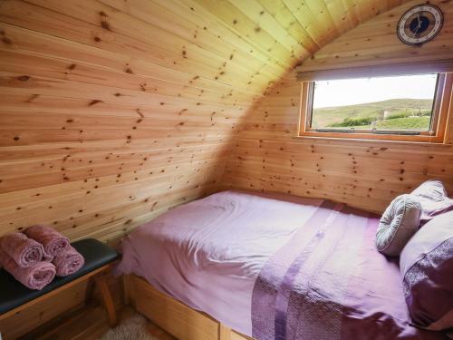 a bed in a wooden room with a window at Pine Lodge in Llangadog