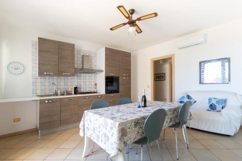 a kitchen and dining room with a table and a ceiling fan at Residence Fior di Sulcis in Calasetta