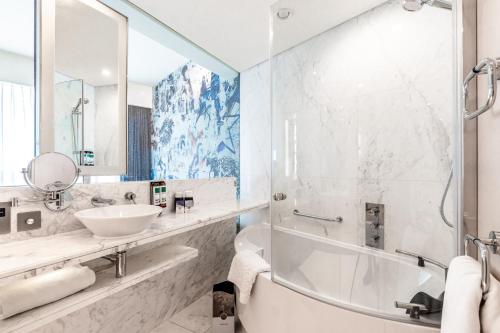 a bathroom with a sink and a tub and a mirror at Media One Hotel in Dubai