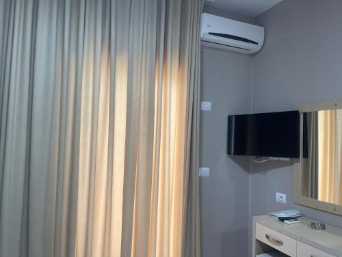 a bathroom with a shower curtain and a television at Season Inn in Dhërmi