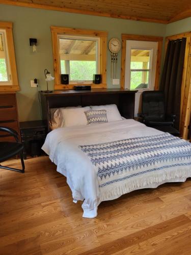 a large bed in a room with two windows at Serene Westside Tiny Cabin in Clinton