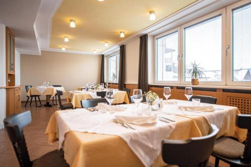 a dining room with tables and chairs and windows at Gasthof Teiser Stern in Funes