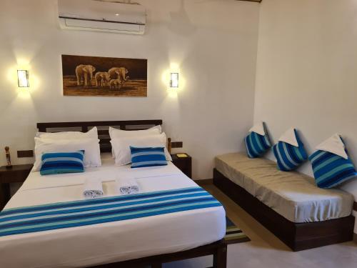 a bedroom with two beds with blue and white pillows at Ranakeliya Lodge - Yala in Yala