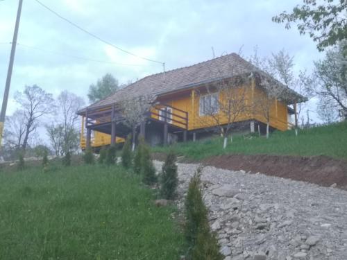 a yellow house on top of a hill with a field at Lake House Anemona in Buhalniţa