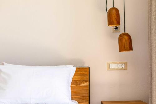 a bedroom with a bed with a white pillow and two lights at Ariadne Hotel in Agios Prokopios