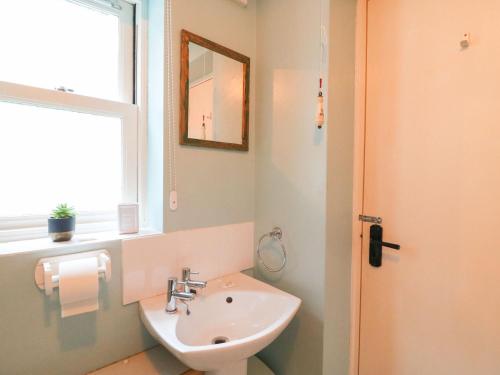 une salle de bain avec un lavabo, un miroir et une fenêtre dans l'établissement Pixie Cottage, à Weymouth