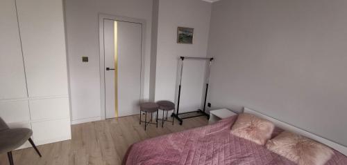 a bedroom with a bed and two stools in it at Apartament Iława Centrum in Iława