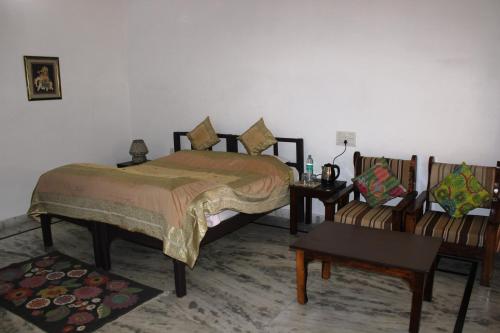 1 dormitorio con 1 cama, 2 sillas y mesa en Royal Farm Bharatpur en Bharatpur