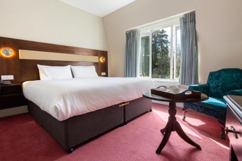 una camera da letto con un letto grande e una sedia di The Glendalough Hotel a Laragh