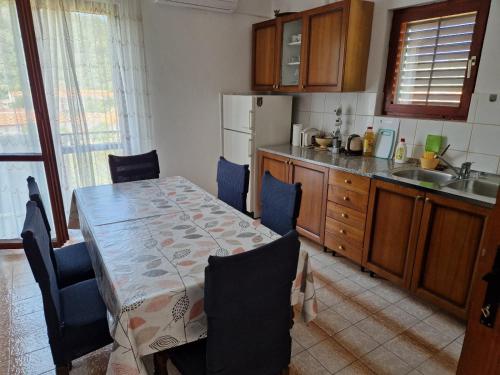 eine Küche mit einem Tisch und Stühlen sowie eine Küche mit einem Waschbecken in der Unterkunft Apartment Opaćac Veli Iž in Veli Iž