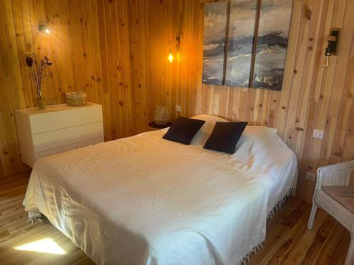 - une chambre avec un grand lit blanc et des murs en bois dans l'établissement L'ESQUIF, à Le Port-des-Barques