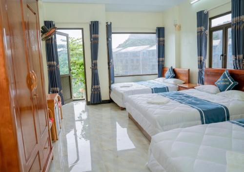 a bedroom with three beds and a large window at Long Thành Motel in Cat Ba